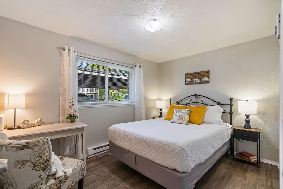 Bedroom with a made bed, lamps, and natural light